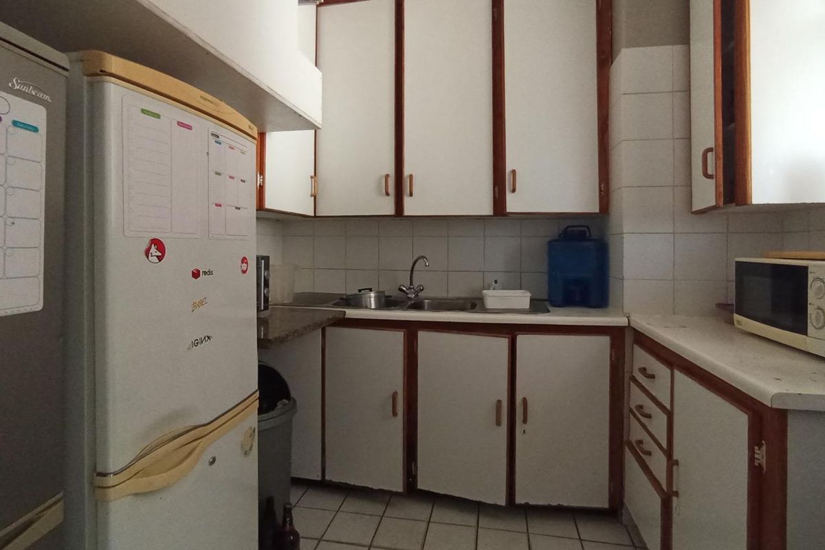 A functional kitchen featuring white cabinetry with wood trim, tiled backsplash, and tiled flooring, offering a dated aesthetic ready for modernization.