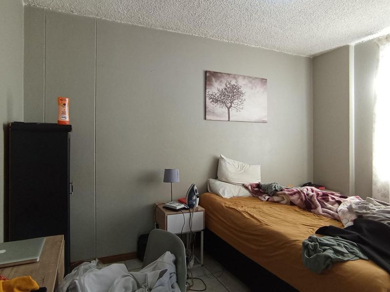 A bedroom featuring tiled flooring and a textured ceiling, currently requiring cosmetic updates to improve the overall finish and appeal.