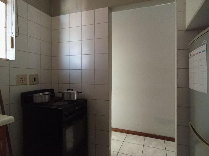 A functional kitchen area featuring tiled walls, tiled flooring, and a freestanding stove, providing a practical space for meal preparation.