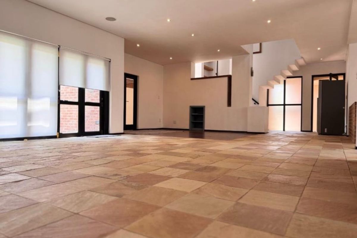 Spacious open-plan living area featuring natural stone tile flooring, recessed lighting, and a modern staircase, offering a bright and versatile blank canvas.