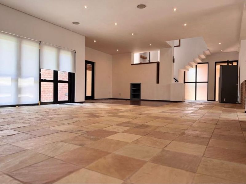 Spacious open-plan living area featuring natural stone tile flooring, recessed lighting, and a modern staircase, offering a bright and versatile blank canvas.
