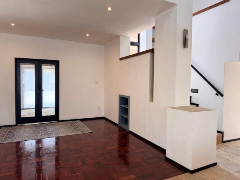 Spacious living area featuring polished parquet flooring, recessed lighting, built-in shelving, and a staircase leading to the upper level.