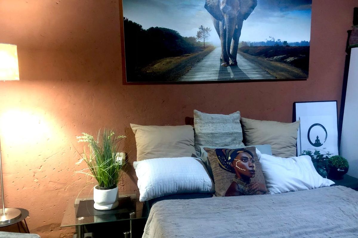 A bedroom featuring a textured terracotta-colored wall and a standard electrical outlet.