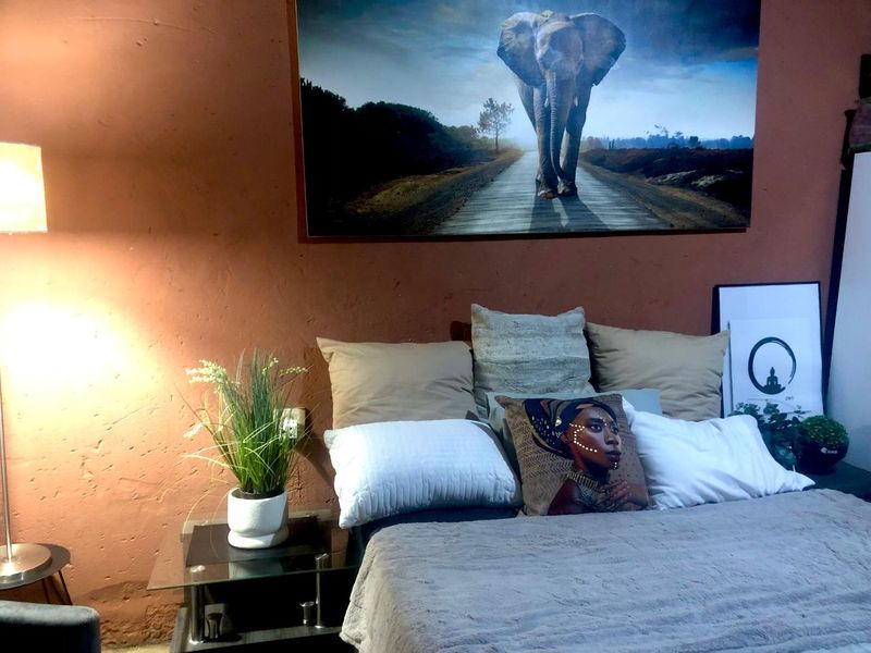 A bedroom featuring a textured terracotta-colored wall and a standard electrical outlet.