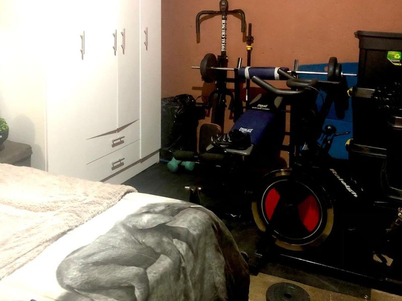 A bedroom featuring a built-in wardrobe, currently utilized as a multi-purpose space with exercise equipment.