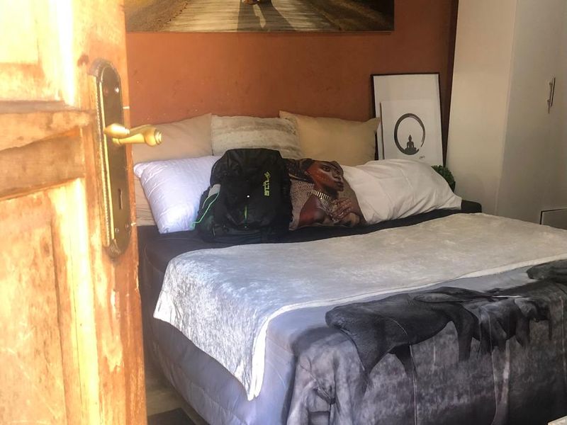 A bedroom featuring a solid wood door with brass hardware and painted walls, requiring minor cosmetic updates to improve the overall aesthetic.