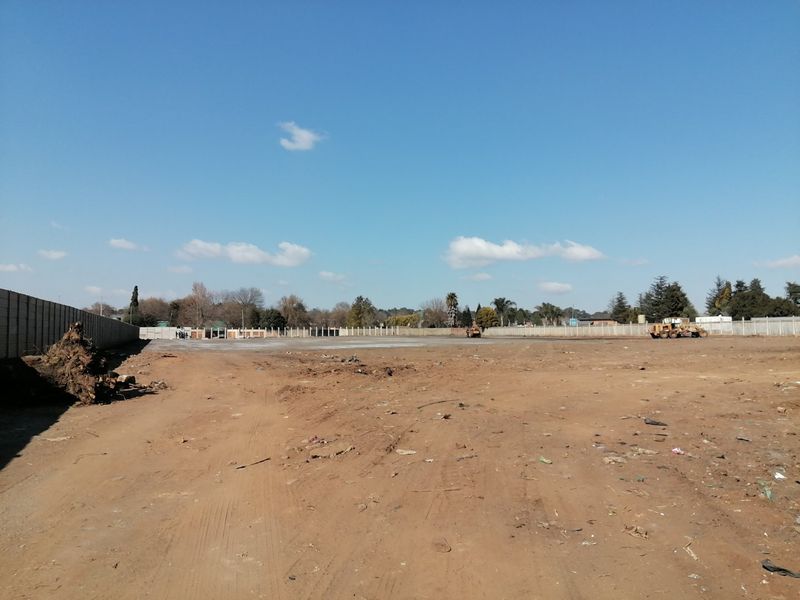 A large, cleared residential vacant land plot enclosed by precast concrete boundary walls, ready for development.