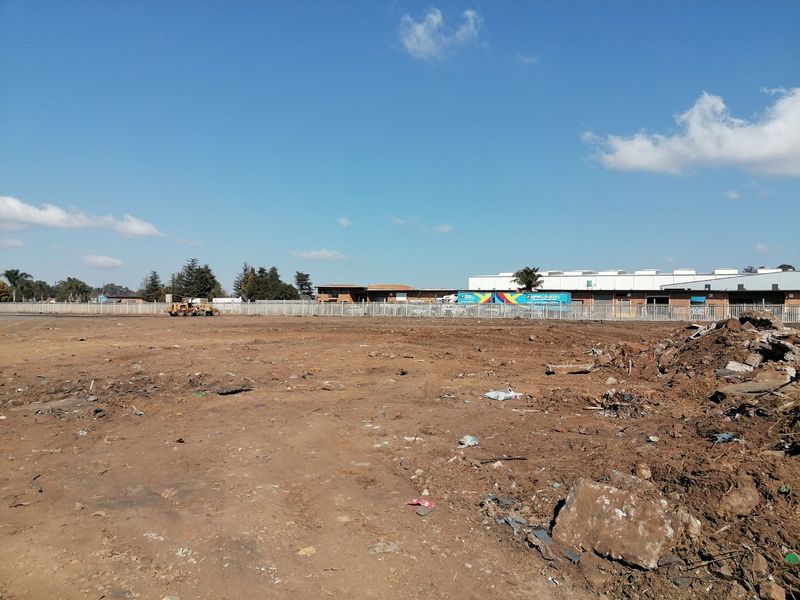 A view of a vacant residential land plot featuring perimeter fencing and cleared ground, ready for development.