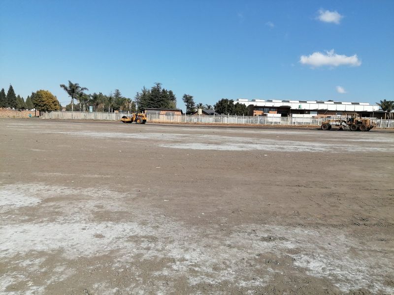 A wide view of a vacant residential plot currently undergoing site preparation and leveling with heavy machinery.