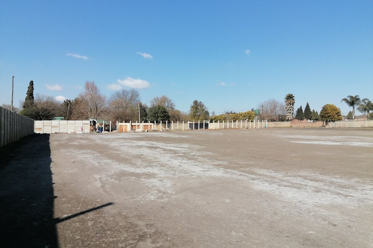 A large, level, and cleared vacant residential plot enclosed by precast concrete boundary walls, ready for development.