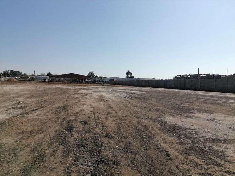 A large, level vacant residential plot featuring a precast concrete boundary wall, ready for development.