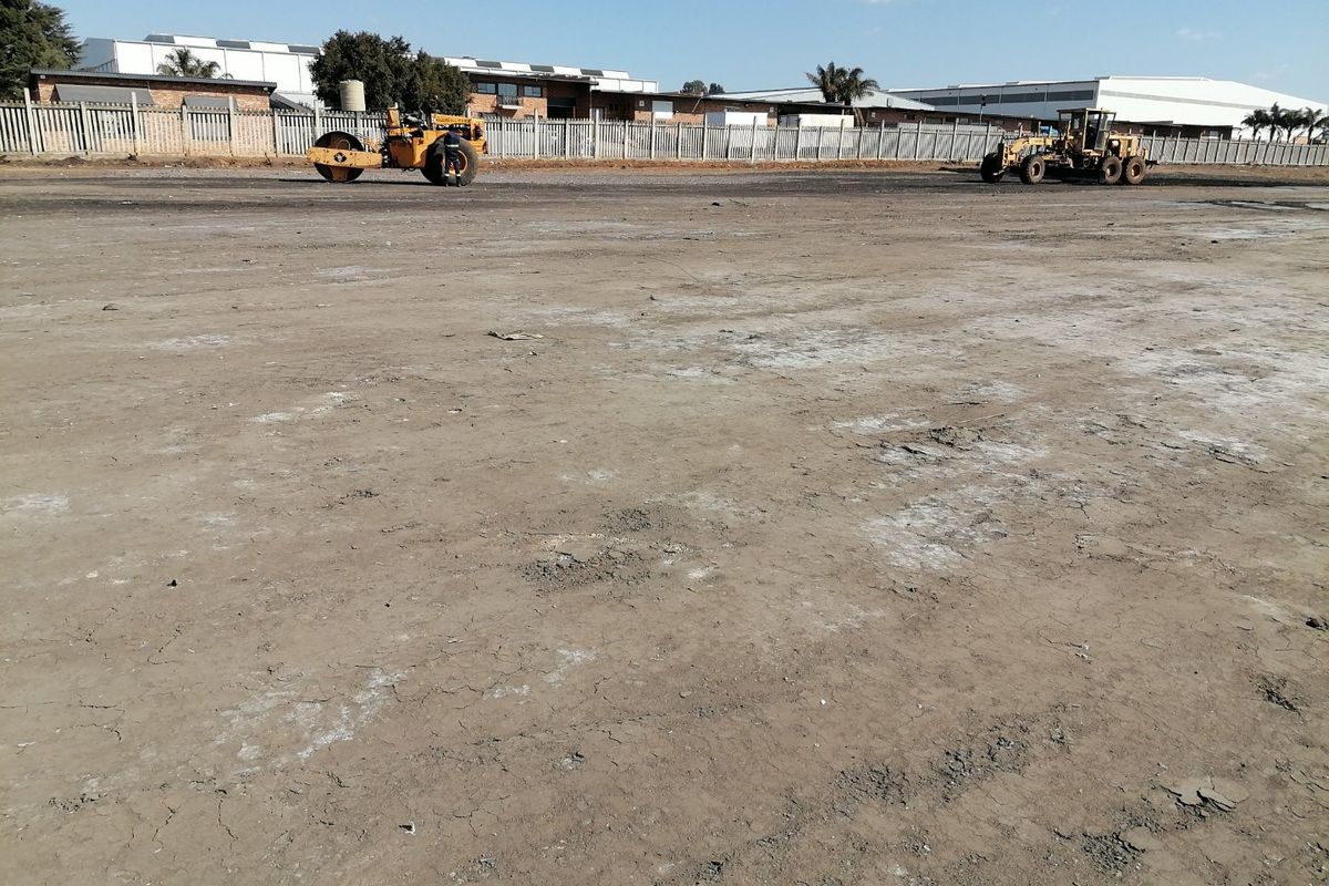 A view of a vacant residential land plot featuring cleared ground and perimeter fencing, currently undergoing site preparation with heavy machinery.