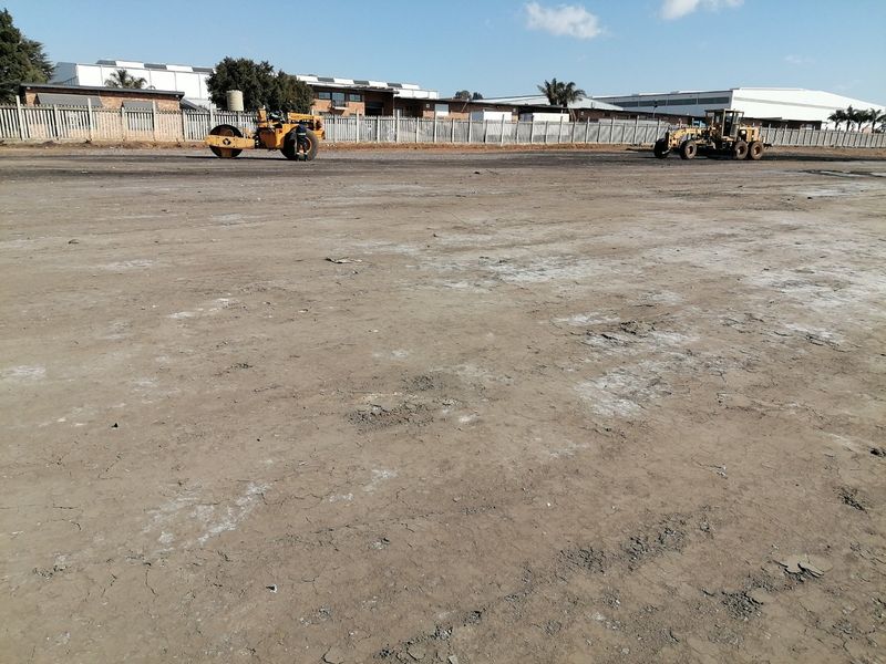 A view of a vacant residential land plot featuring cleared ground and perimeter fencing, currently undergoing site preparation with heavy machinery.