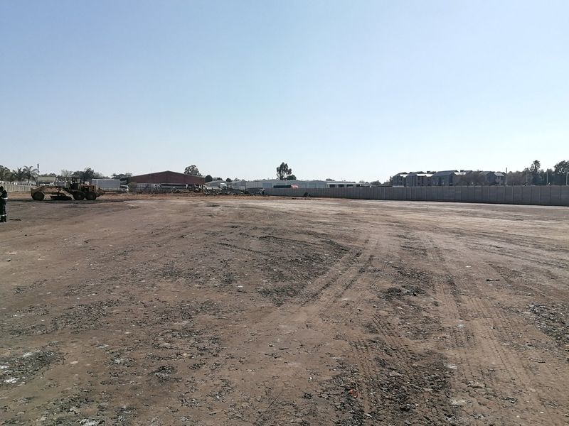 A large, cleared vacant residential plot featuring a perimeter wall and level ground, ready for development.