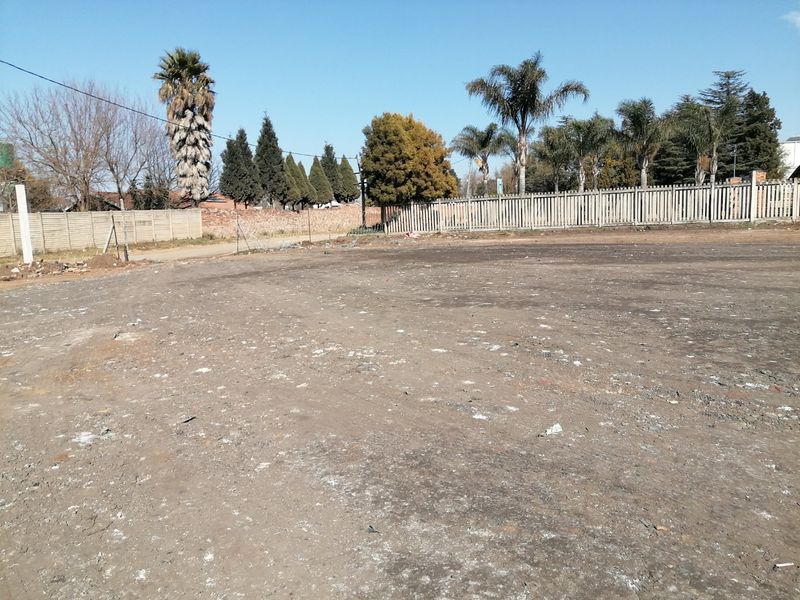 A vacant residential plot featuring a cleared ground surface and perimeter boundary walling, ready for future development.
