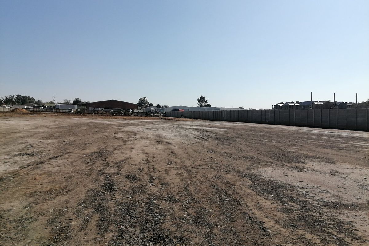 A large, level vacant residential plot featuring a precast concrete boundary wall, ready for development.