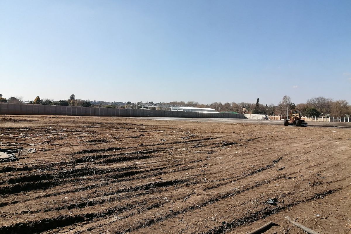 A large, cleared residential vacant land plot featuring a perimeter wall and level ground, ready for development.