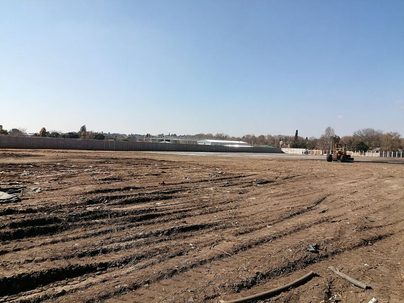 A large, cleared residential vacant land plot featuring a perimeter wall and level ground, ready for development.