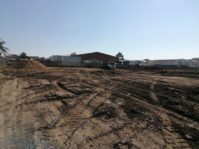A large, cleared vacant residential plot of land with perimeter fencing, ready for development.