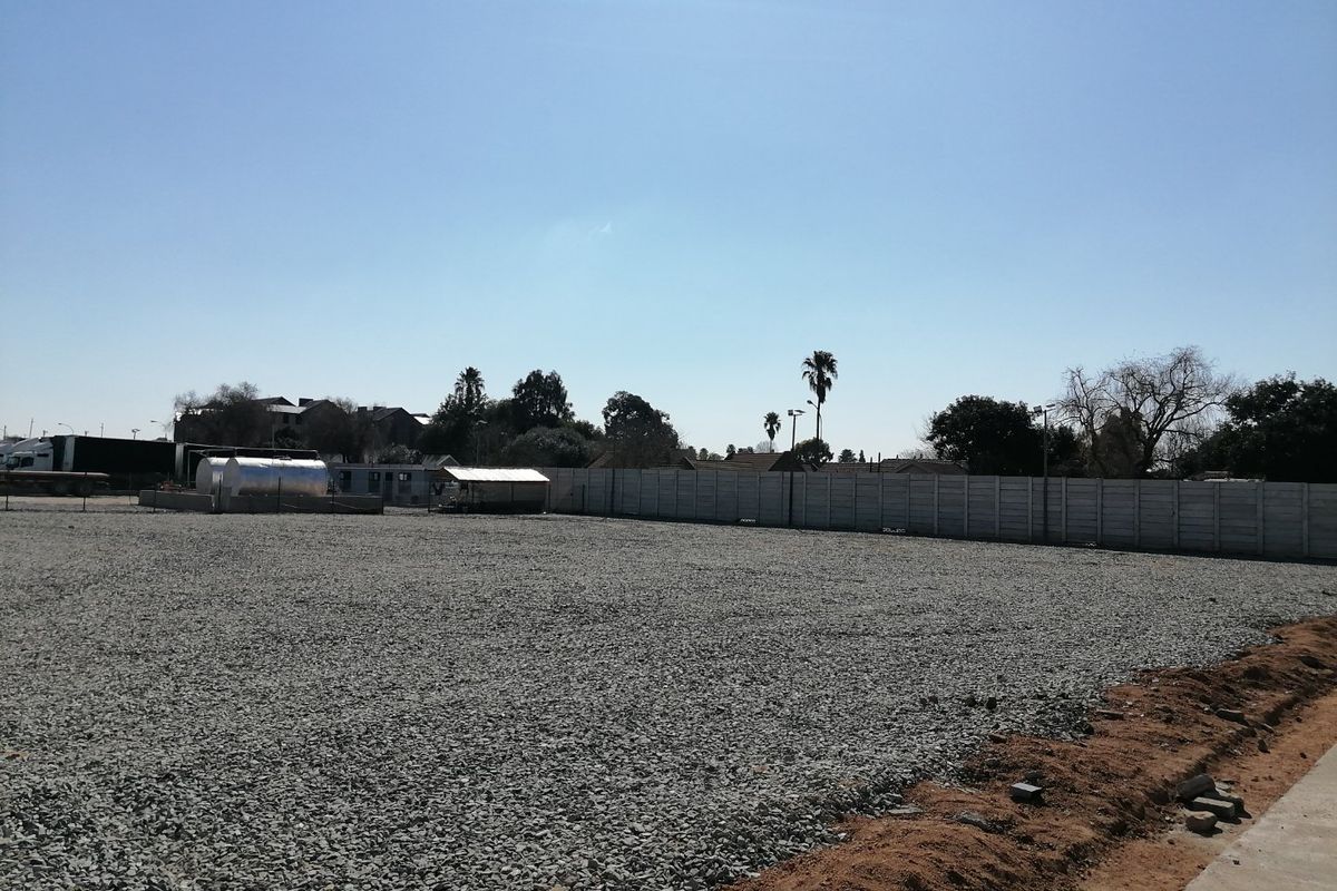 A level, gravel-surfaced vacant residential plot enclosed by a precast concrete boundary wall, suitable for development.
