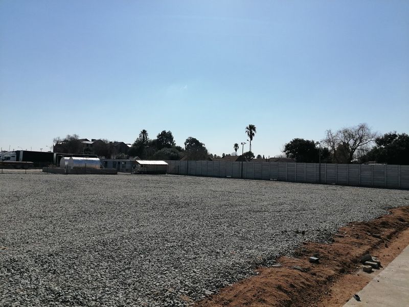 A level, gravel-surfaced vacant residential plot enclosed by a precast concrete boundary wall, suitable for development.