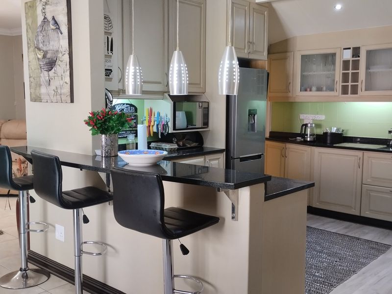 Open-plan kitchen featuring granite countertops, ample built-in cabinetry, and a breakfast bar, seamlessly flowing into the adjacent living area.