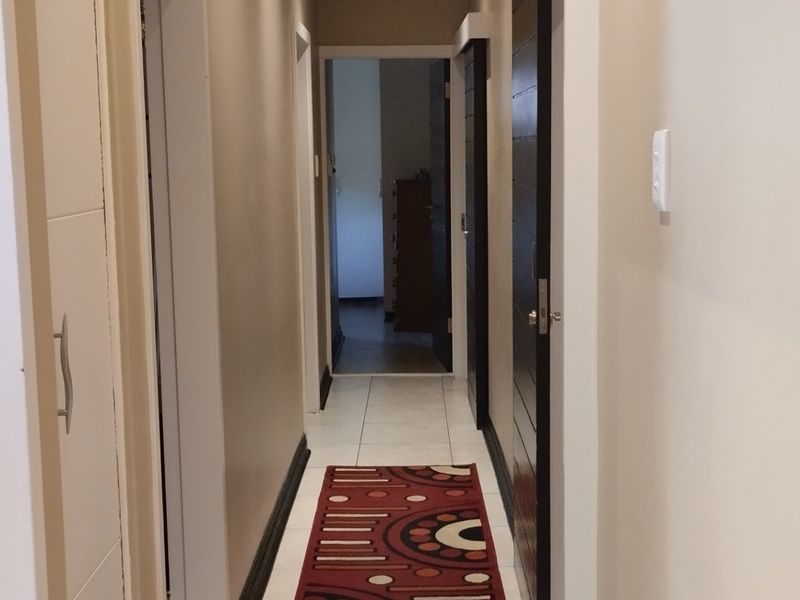 A well-lit hallway featuring tiled flooring, recessed downlights, and integrated built-in storage cupboards, providing a clean and functional transition space.