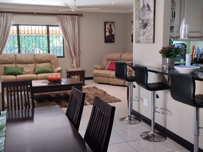 Open-plan living and dining area featuring tiled floors, a breakfast bar with granite countertops, and a connected kitchen space.