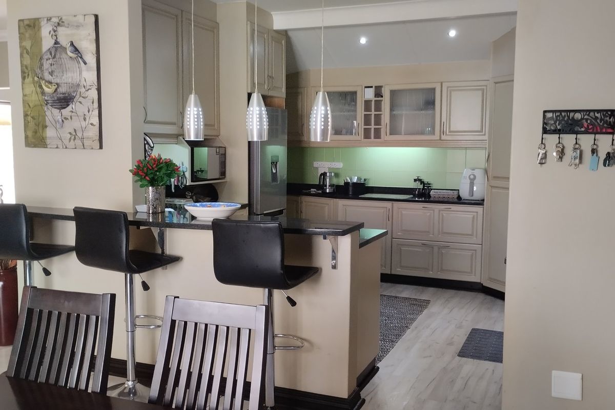 A functional kitchen featuring neutral cabinetry, granite countertops, a breakfast bar with pendant lighting, and a tiled backsplash, seamlessly integrated into the living space.