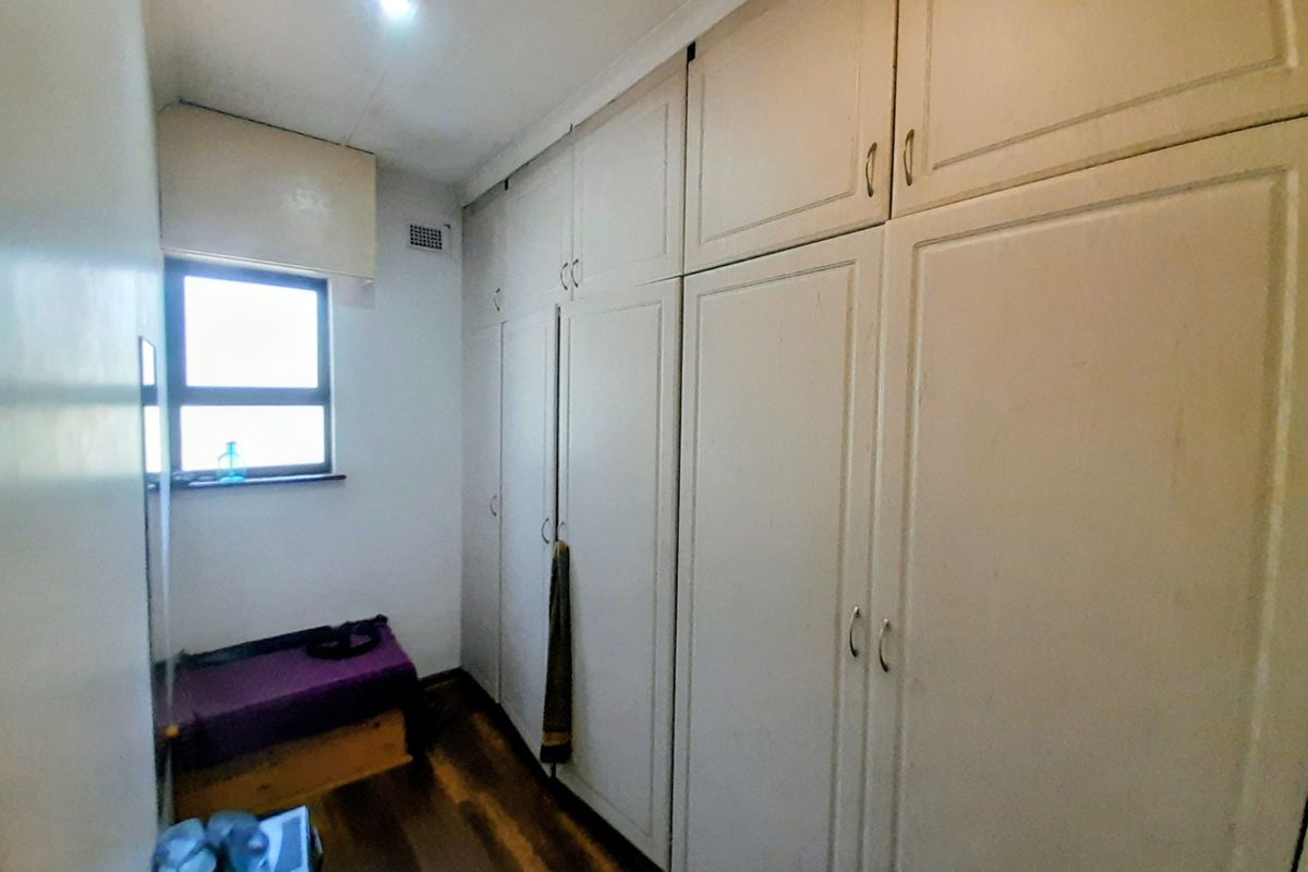 A bedroom featuring extensive built-in cupboards, laminate flooring, and a window providing natural light.