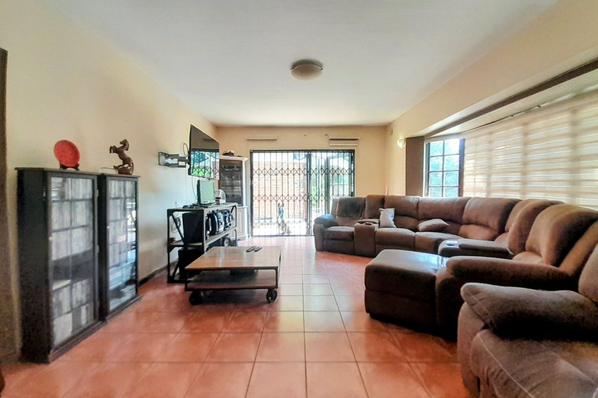 Spacious living room featuring ceramic tile flooring, air conditioning, and a sliding glass door leading to the exterior with a security gate.