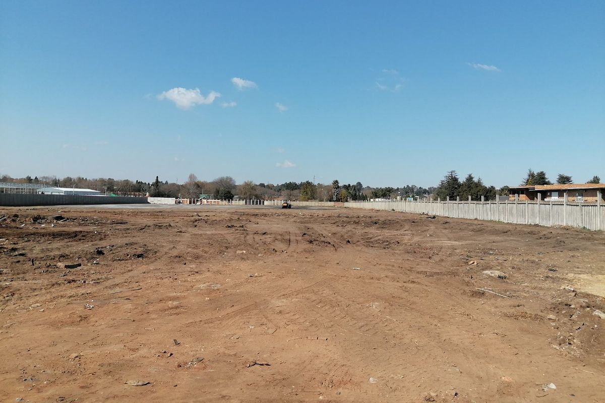 A vacant residential plot of land featuring cleared earth and perimeter precast concrete boundary walls.