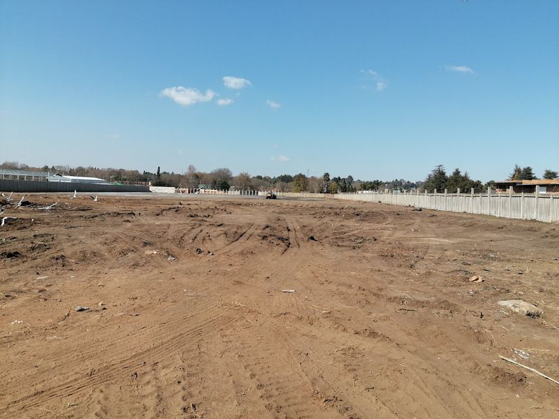 A vacant residential plot of land featuring cleared earth and concrete perimeter fencing, ready for development.