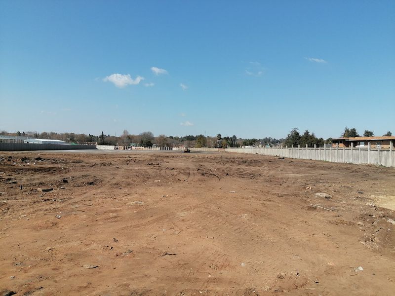 A vacant residential plot of land featuring cleared earth and perimeter precast concrete boundary walls.