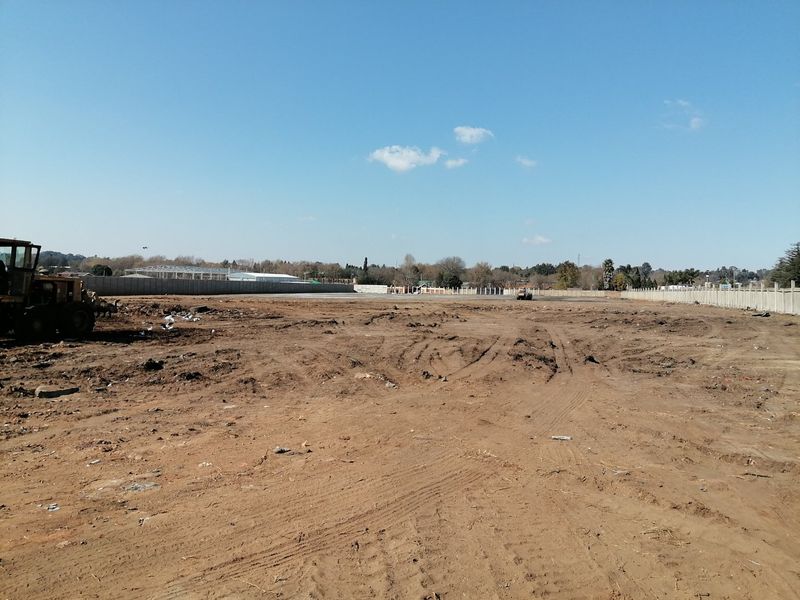 A large, cleared residential vacant land plot featuring a perimeter precast concrete boundary wall and levelled ground, ready for development.