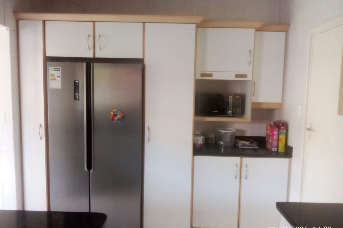 A functional kitchen area featuring white built-in cabinetry, dark granite countertops, and a built-in microwave space.