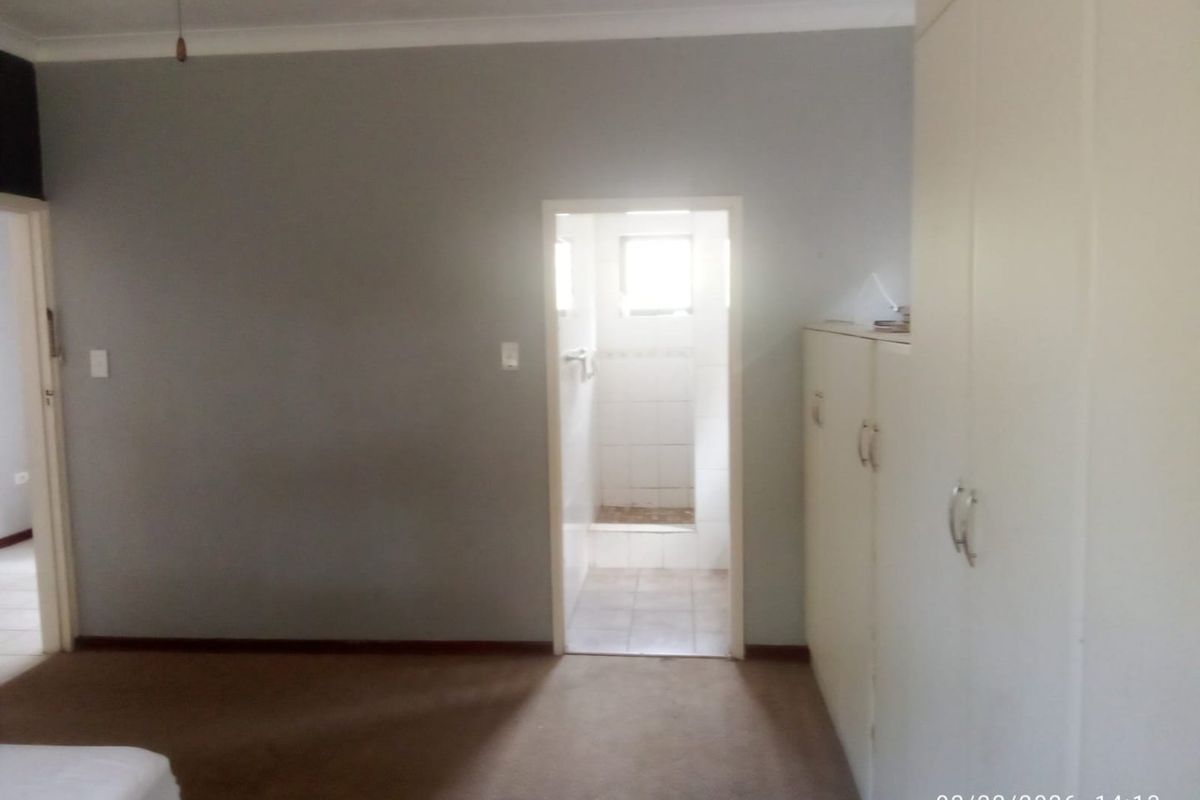 A spacious bedroom featuring built-in cupboards, carpeted flooring, and direct access to an en-suite bathroom.