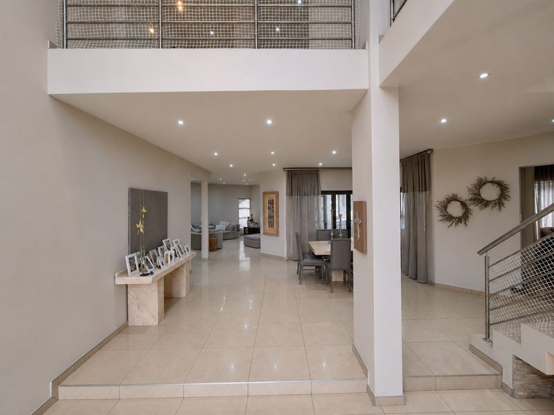 Spacious open-plan living area featuring tiled floors, recessed lighting, and a mezzanine level with a modern metal balustrade.
