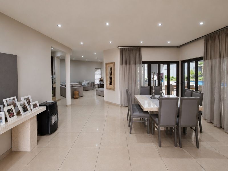 Spacious open-plan dining area featuring tiled floors, recessed lighting, and large sliding glass doors providing seamless access to the outdoor patio and pool area.