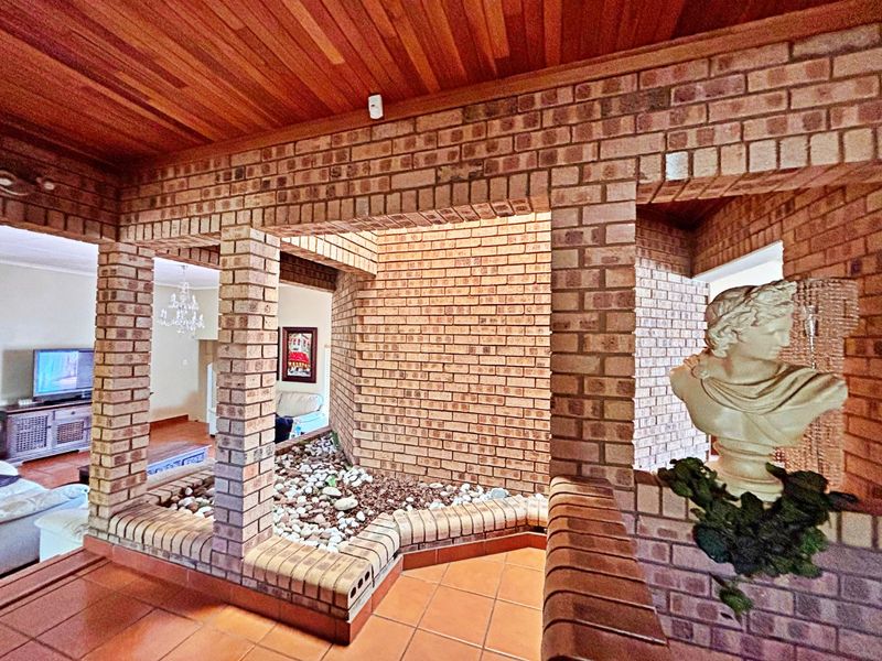 Entrance foyer featuring distinctive exposed brickwork, a warm timber-clad ceiling, and a built-in indoor planter bed with terracotta flooring.