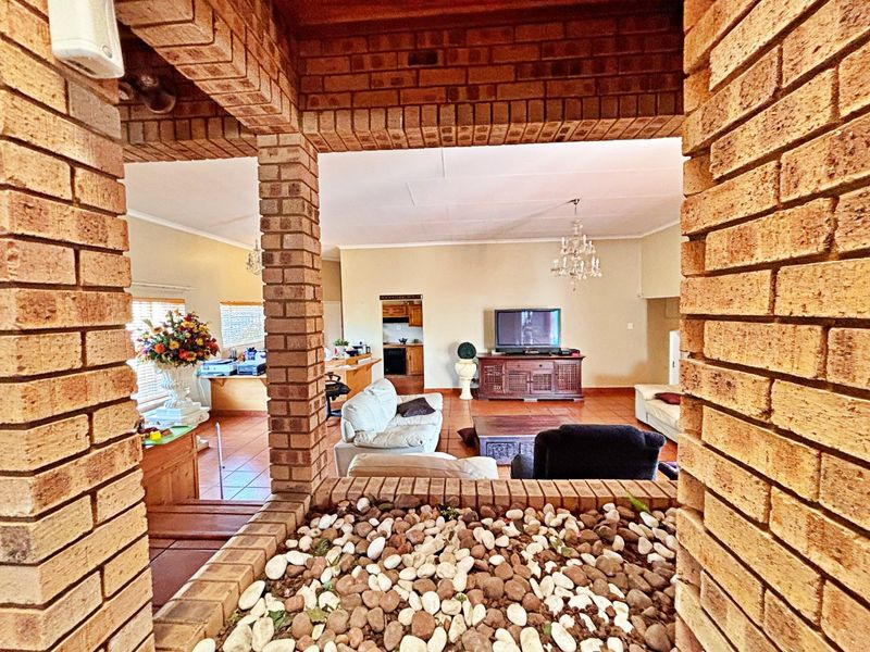 Spacious open-plan living area featuring exposed brick pillars, terracotta flooring, and a unique built-in indoor planter, creating a rustic and character-filled interior space.