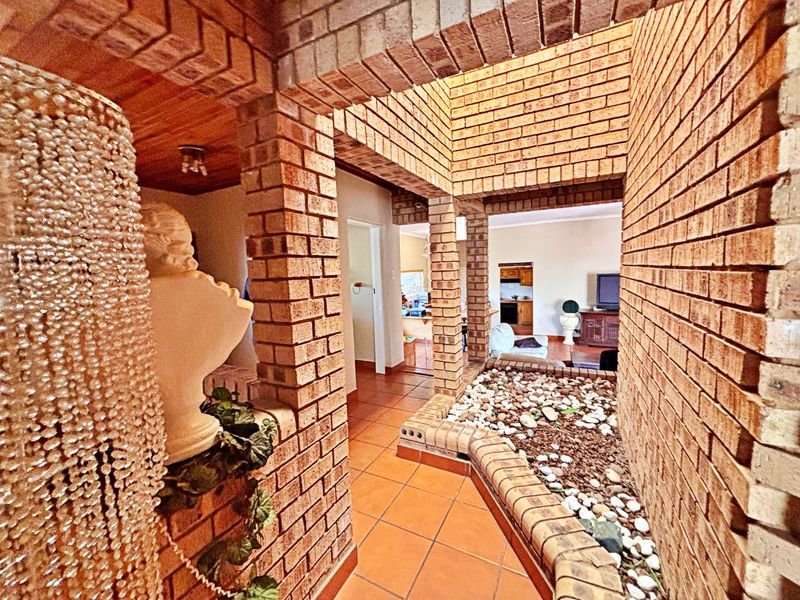 Unique entrance hall featuring exposed brick walls, terracotta tiling, and a built-in indoor rock garden feature with decorative brick archways.