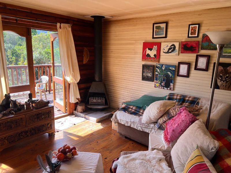 Cozy living room featuring warm timber wall paneling, hardwood floors, and a built-in wood-burning fireplace with direct access to an outdoor deck.