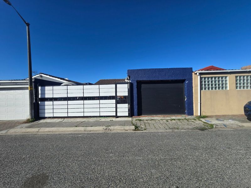 Front exterior view showing a roller garage door, white sliding gate, and glass block window detail on the street-facing facade.