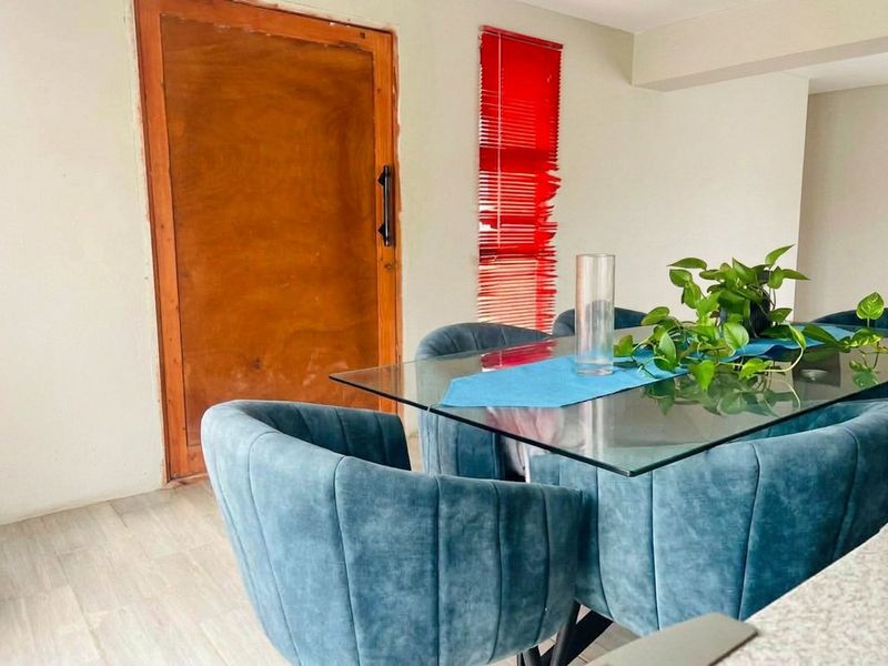Dining area featuring tiled flooring, a wooden door with an unfinished frame, and red venetian blinds.