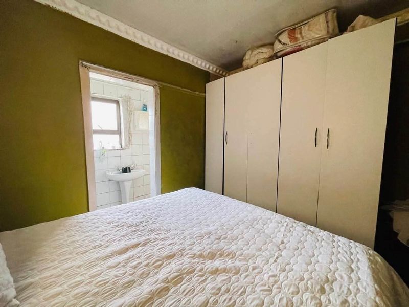 Bedroom featuring built-in wardrobes and crown molding, with an adjoining en-suite bathroom area containing a pedestal sink.