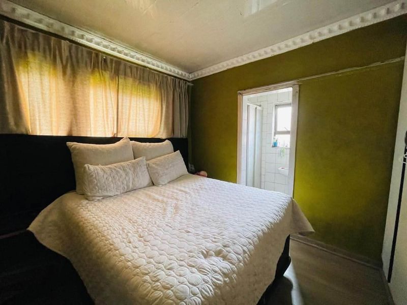 Bedroom featuring crown molding and direct access to an en-suite bathroom, requiring cosmetic updates to wall finishes and ceiling.