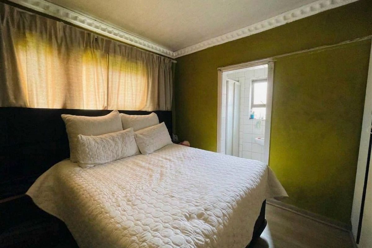 A bedroom featuring crown molding, laminate flooring, and direct access to an en-suite bathroom.