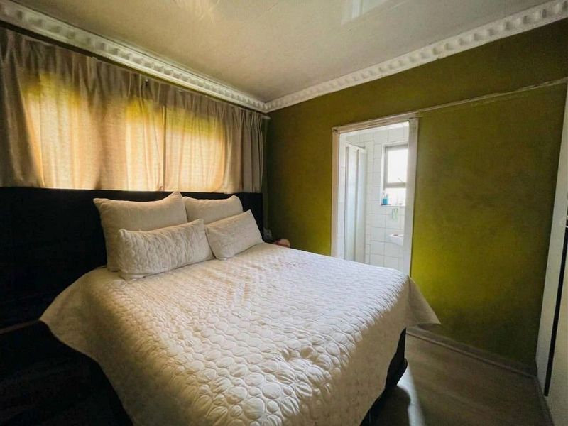 A bedroom featuring crown molding, laminate flooring, and direct access to an en-suite bathroom.