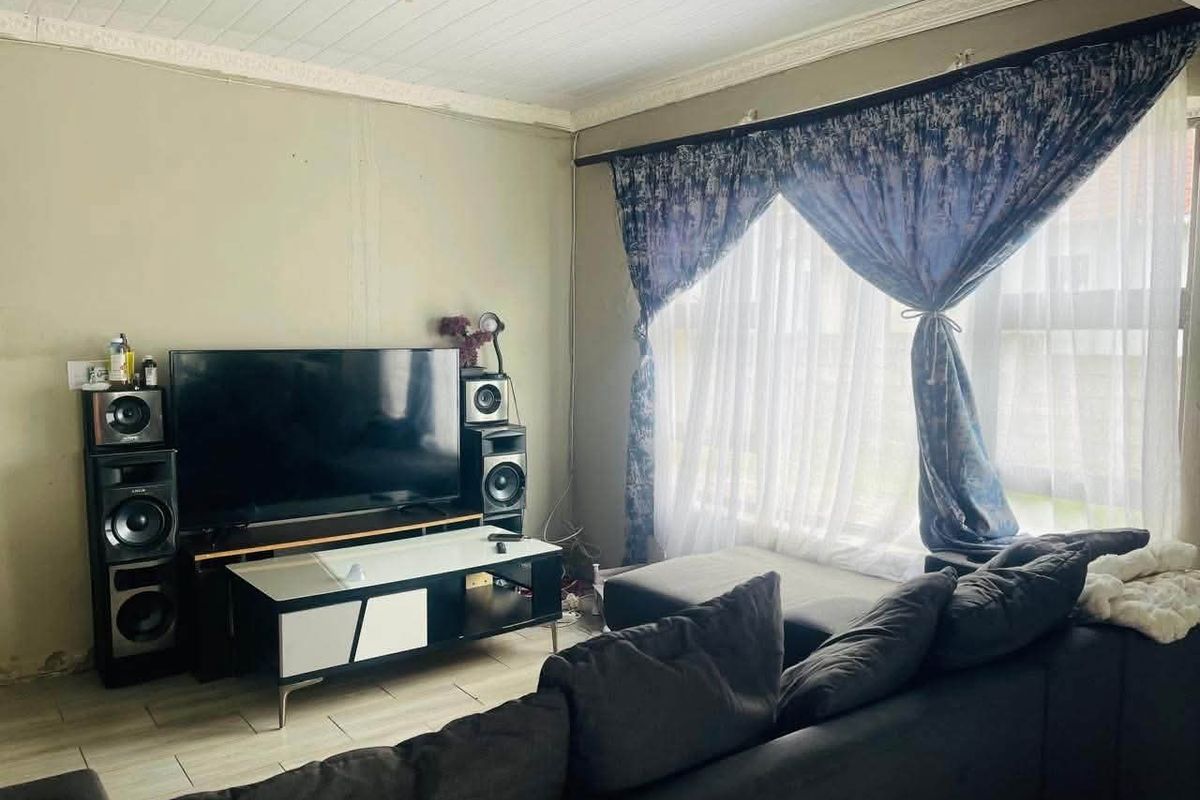 A living room featuring tiled flooring and a tongue and groove ceiling, requiring cosmetic updates to the wall finishes.
